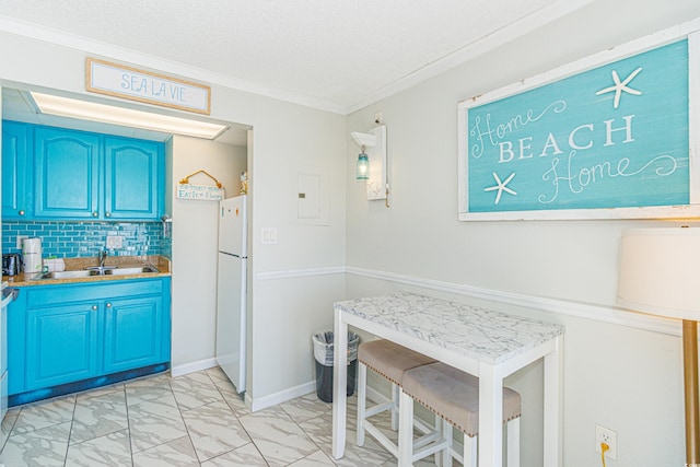 kitchen featuring blue cabinets, sink, crown molding, white fridge, and backsplash