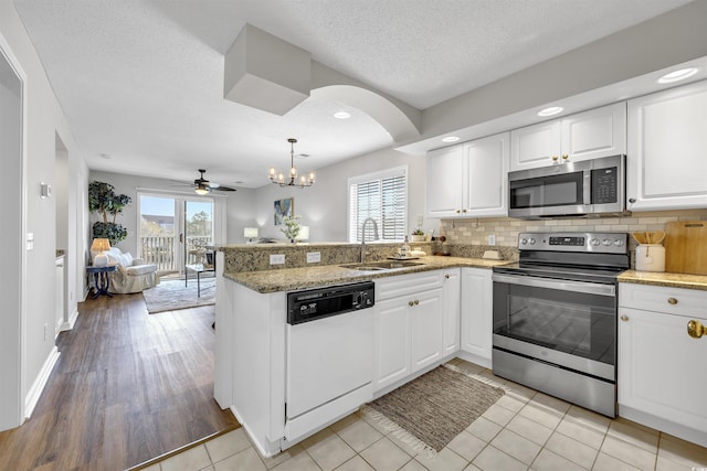 kitchen featuring sink, appliances with stainless steel finishes, white cabinetry, backsplash, and kitchen peninsula