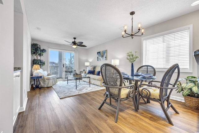 dining room with hardwood / wood-style floors, ceiling fan with notable chandelier, and a textured ceiling