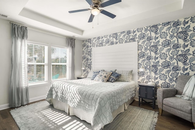 bedroom with a raised ceiling, dark hardwood / wood-style flooring, and ceiling fan