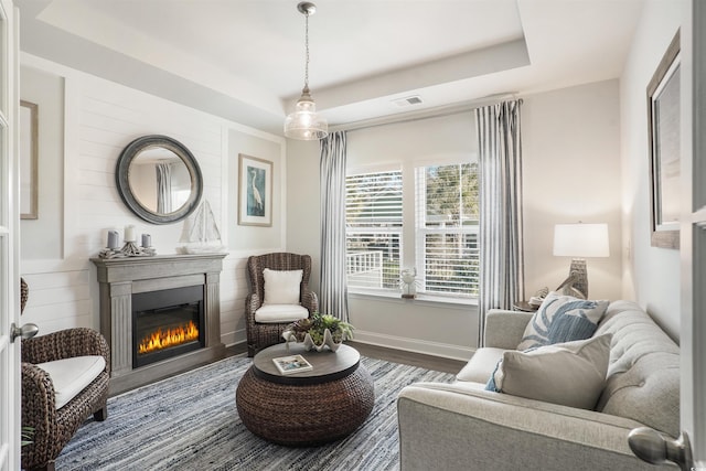 sitting room featuring wood-type flooring and a tray ceiling