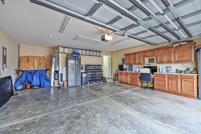 garage with stainless steel refrigerator, a garage door opener, electric panel, and a workshop area