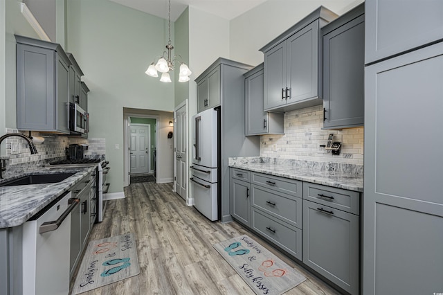 kitchen with high end appliances, gray cabinets, sink, and light stone counters