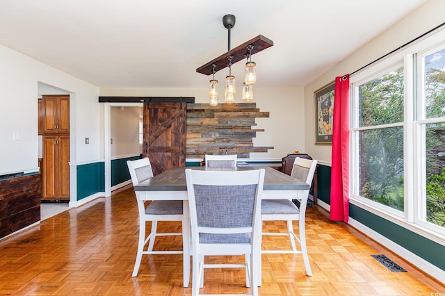 dining space with a barn door and parquet floors