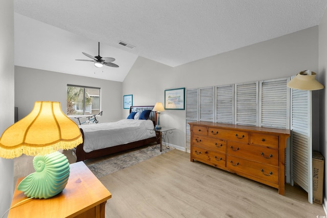 bedroom with ceiling fan, lofted ceiling, light hardwood / wood-style floors, and a textured ceiling