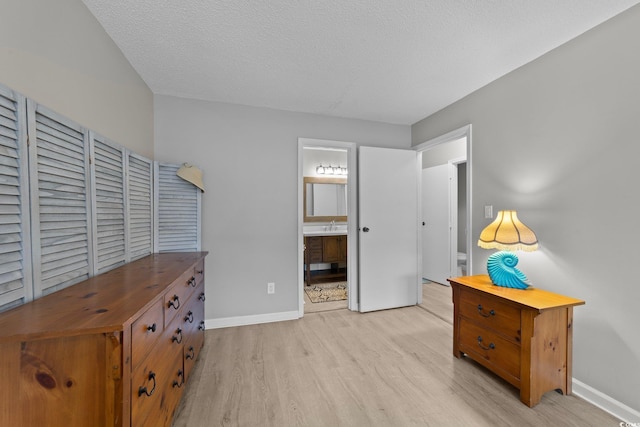 bedroom with connected bathroom, sink, a textured ceiling, and light wood-type flooring