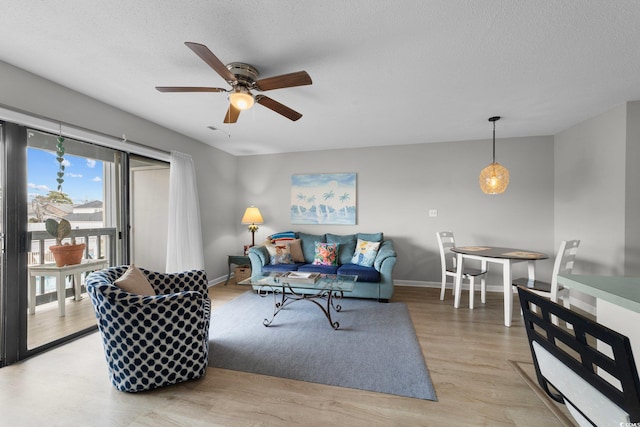 living room with ceiling fan, light hardwood / wood-style floors, and a textured ceiling