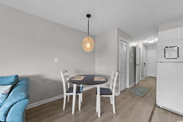 dining room featuring light hardwood / wood-style flooring and a textured ceiling