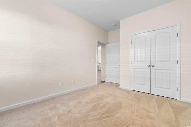 unfurnished bedroom featuring light carpet and a closet