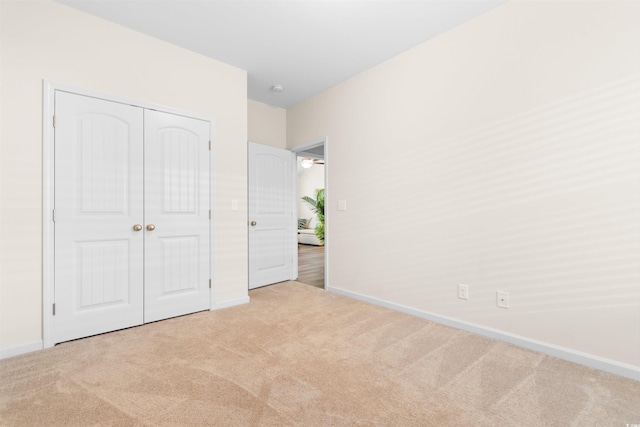 unfurnished bedroom with light colored carpet and a closet