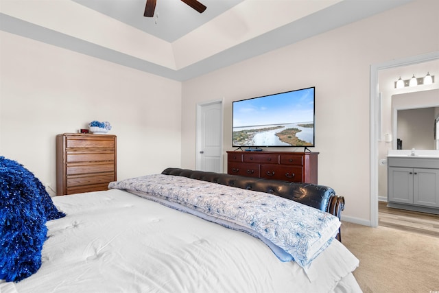 carpeted bedroom with ceiling fan, ensuite bathroom, a raised ceiling, and sink