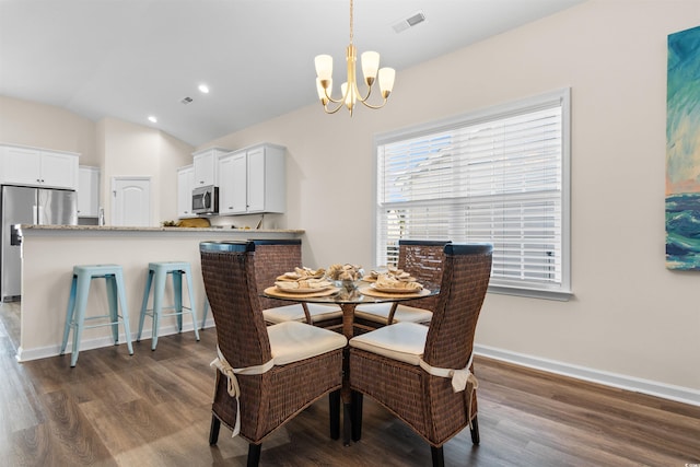 dining area featuring dark wood-type flooring, vaulted ceiling, and a notable chandelier