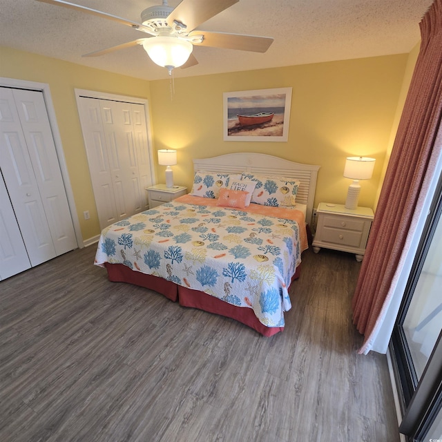 bedroom featuring dark wood-type flooring, ceiling fan, multiple closets, and a textured ceiling