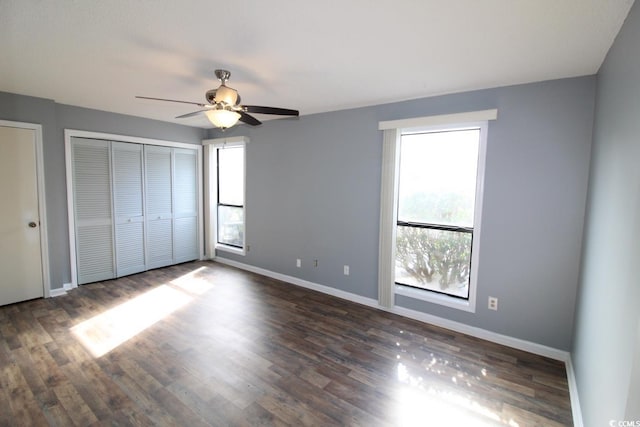 unfurnished bedroom featuring dark hardwood / wood-style floors, two closets, and ceiling fan