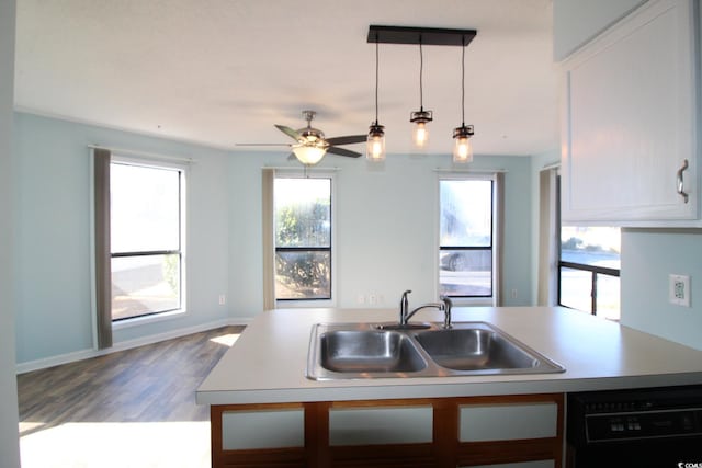 kitchen with sink, wood-type flooring, hanging light fixtures, dishwasher, and an island with sink