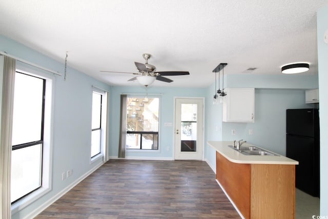 kitchen featuring black refrigerator, decorative light fixtures, white cabinetry, sink, and dark wood-type flooring