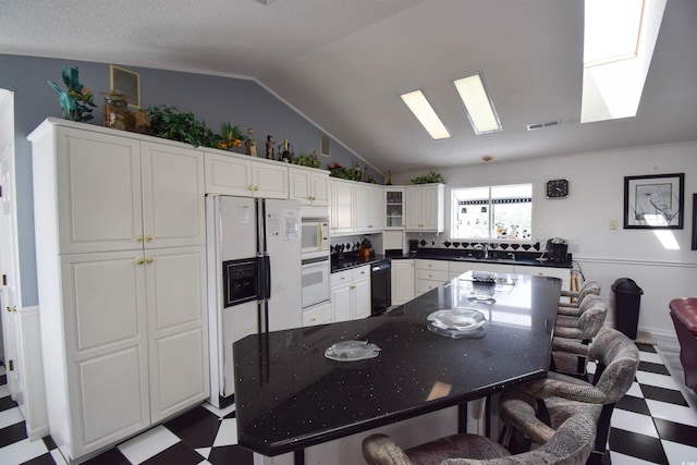 kitchen featuring lofted ceiling, sink, white cabinets, and white appliances