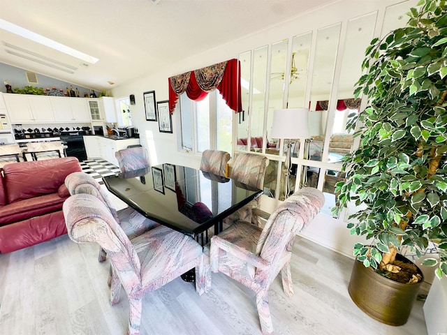 dining area featuring lofted ceiling and light hardwood / wood-style floors