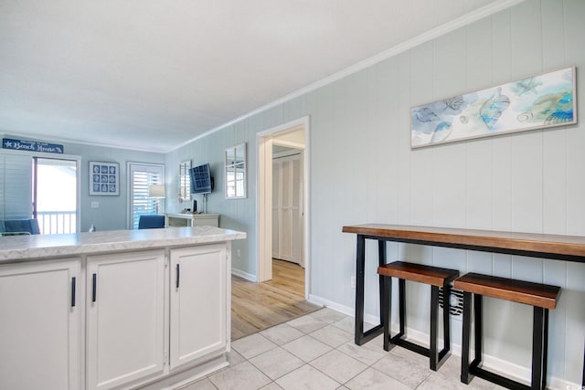 kitchen with white cabinetry, ornamental molding, and light tile patterned flooring