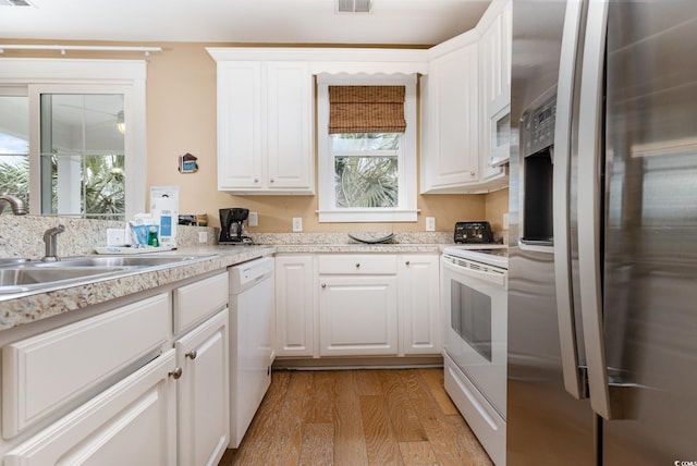 kitchen with white cabinetry, white appliances, light hardwood / wood-style floors, and a wealth of natural light