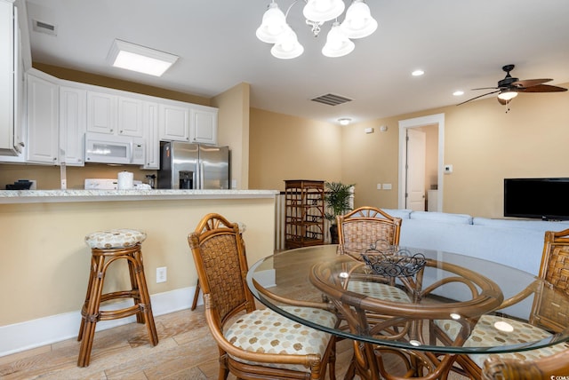 dining area featuring ceiling fan with notable chandelier