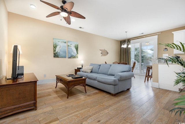 living room with ceiling fan with notable chandelier and light hardwood / wood-style floors