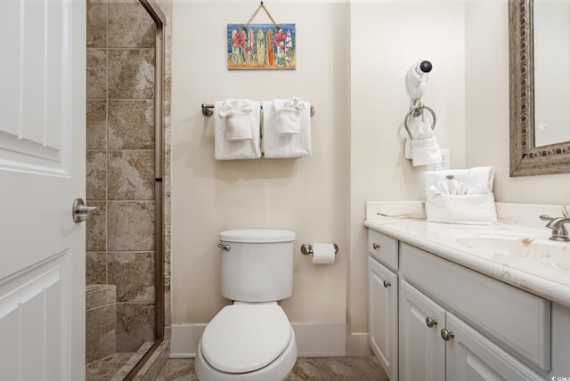 bathroom with tiled shower, vanity, and toilet