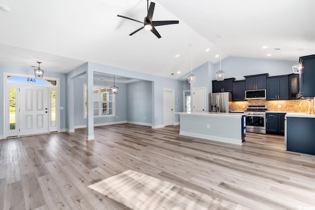 kitchen with a kitchen island, decorative light fixtures, decorative backsplash, light hardwood / wood-style floors, and stainless steel appliances