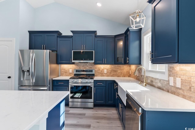 kitchen featuring blue cabinetry, appliances with stainless steel finishes, decorative light fixtures, and vaulted ceiling