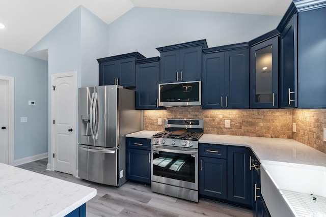 kitchen featuring blue cabinets, tasteful backsplash, high vaulted ceiling, light wood-type flooring, and stainless steel appliances