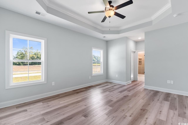 unfurnished room featuring crown molding, ceiling fan, light wood-type flooring, and a tray ceiling