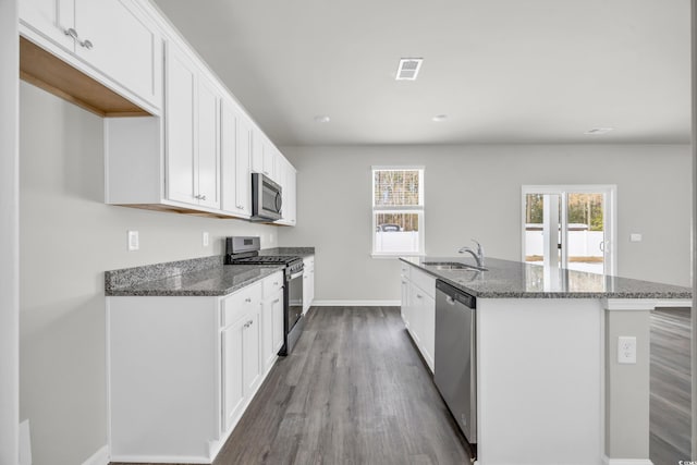 kitchen featuring stainless steel appliances, white cabinetry, sink, and a center island with sink