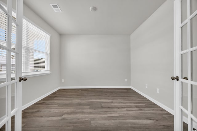 empty room with dark hardwood / wood-style flooring and french doors