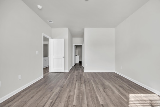 unfurnished room featuring visible vents, baseboards, and wood finished floors