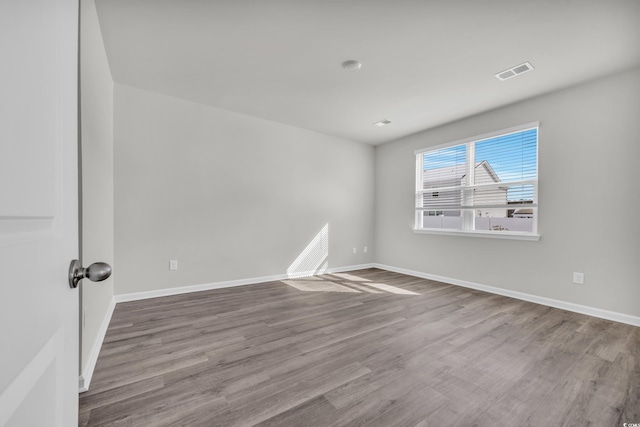 spare room with visible vents, baseboards, and wood finished floors