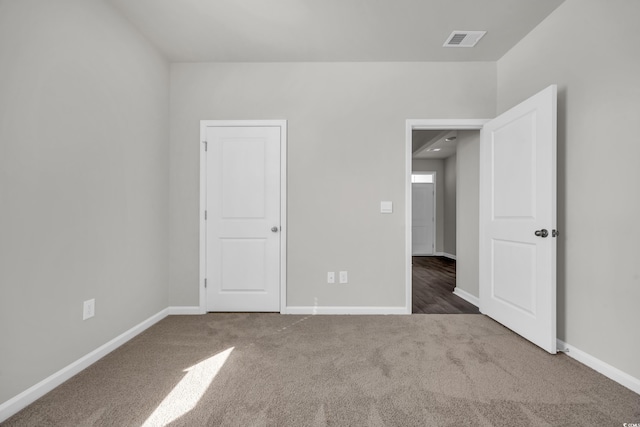 unfurnished bedroom featuring baseboards, visible vents, and dark colored carpet