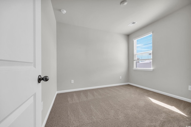 carpeted spare room with visible vents and baseboards