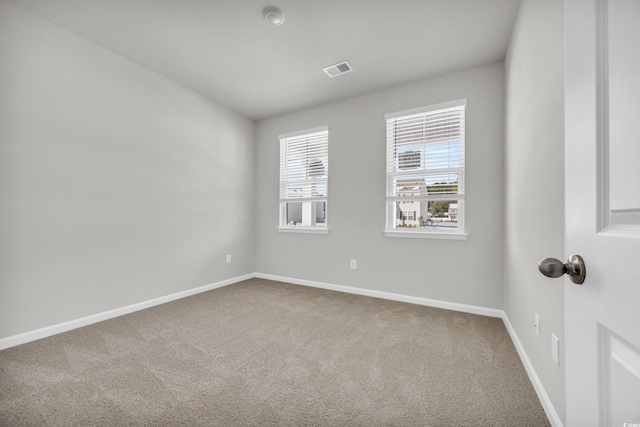 unfurnished room featuring carpet floors, visible vents, and baseboards