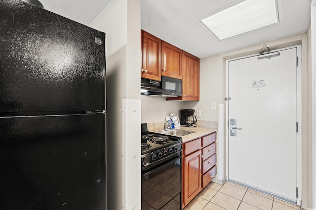 kitchen featuring sink, black appliances, and light tile patterned flooring