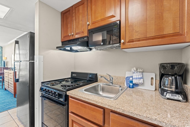 kitchen featuring sink, light tile patterned floors, light stone counters, and black appliances