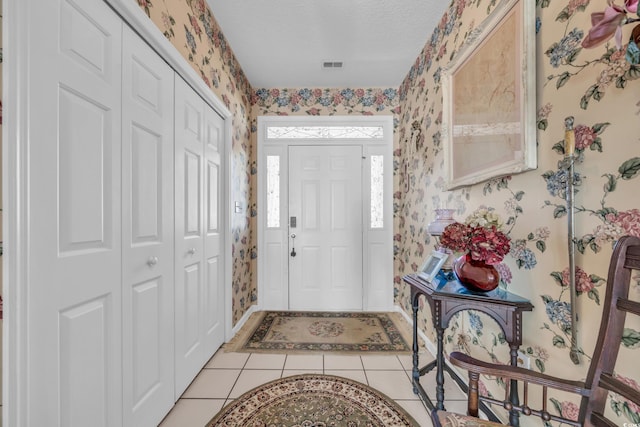 foyer entrance featuring a textured ceiling and light tile patterned floors