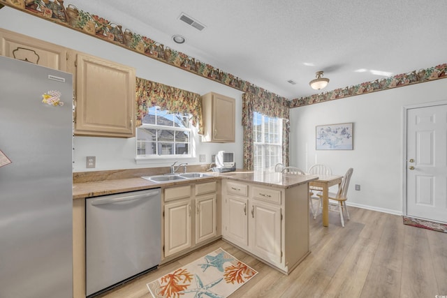 kitchen featuring sink, appliances with stainless steel finishes, a textured ceiling, kitchen peninsula, and light wood-type flooring