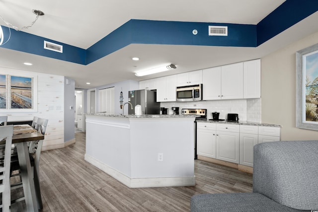 kitchen featuring white cabinetry, appliances with stainless steel finishes, a center island with sink, and light hardwood / wood-style floors