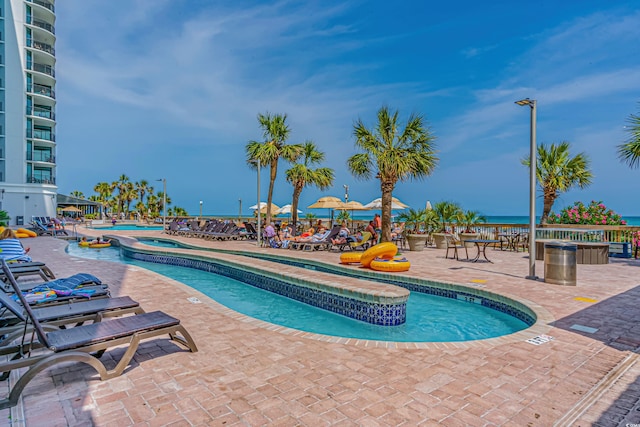 view of pool with a patio area, a hot tub, and a water view