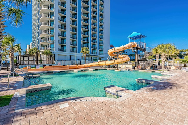 view of pool with a water slide and a patio area