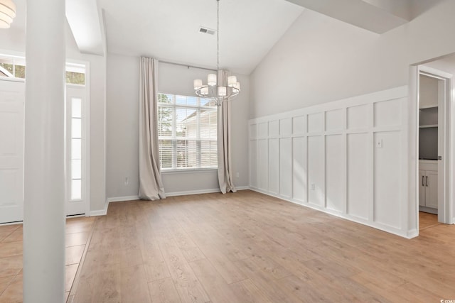 unfurnished dining area featuring vaulted ceiling, a notable chandelier, and light hardwood / wood-style floors