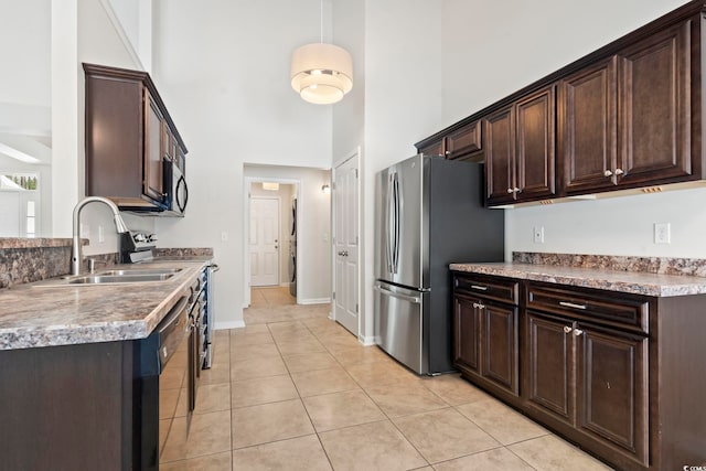 kitchen with light tile patterned floors, dark brown cabinets, and stainless steel appliances