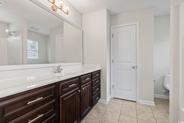 bathroom with vanity, walk in shower, toilet, tile patterned floors, and a textured ceiling