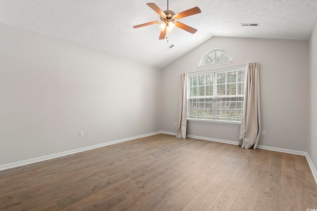 empty room with wood-type flooring, lofted ceiling, a textured ceiling, and ceiling fan