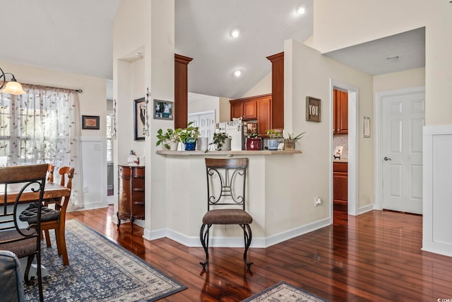 kitchen featuring fridge, lofted ceiling, dark hardwood / wood-style floors, and kitchen peninsula